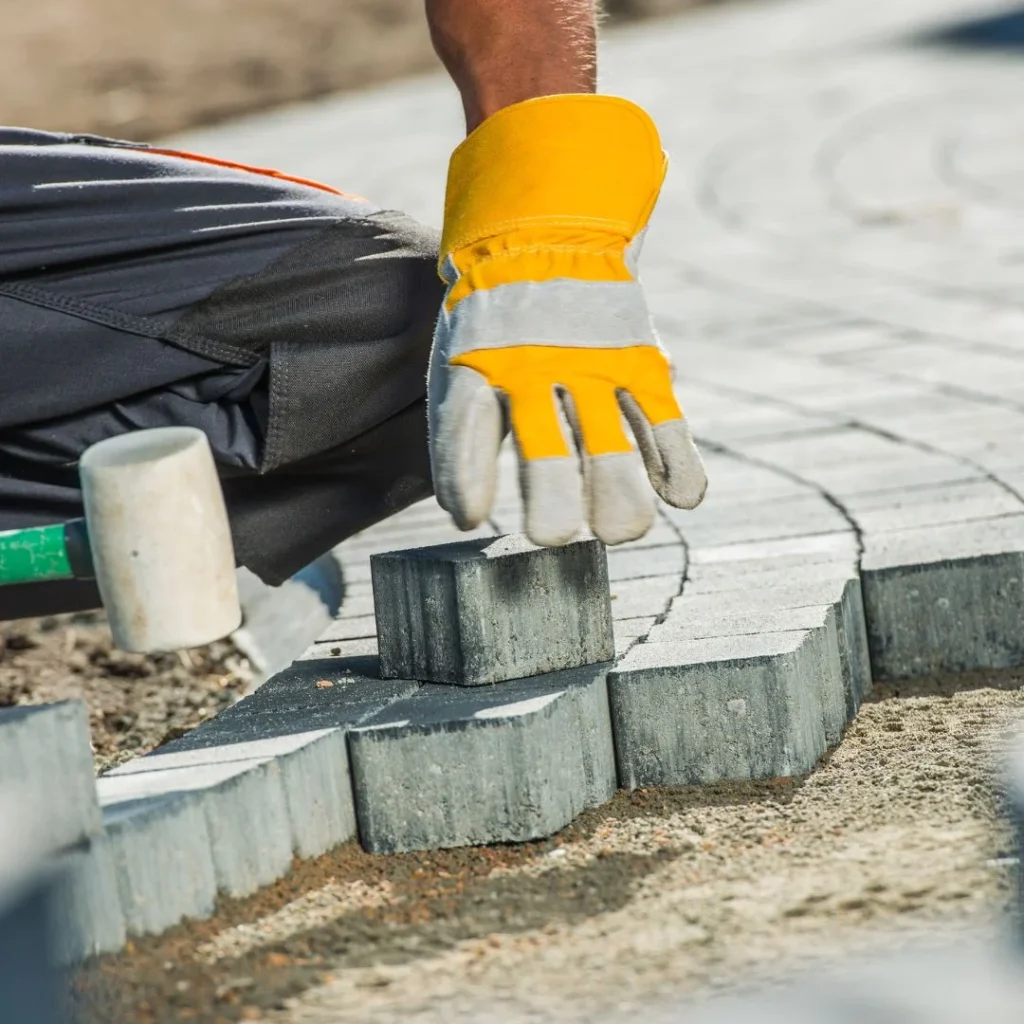 Worker laying paving stones for Concrete Rotorua's Contact Us service.